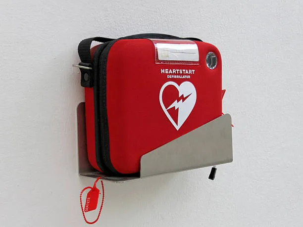 Red Heartstart External Defibrillator Hangs On A White Wall In A Museum In Germany, Nuremberg.